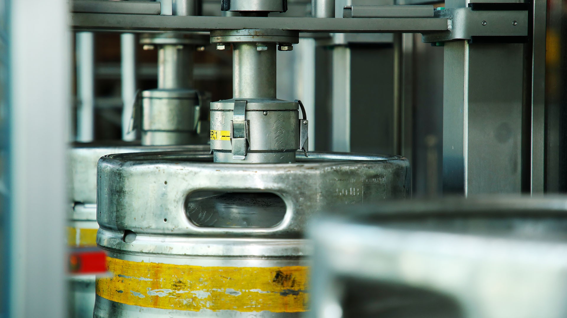 Mehrere Metallfässer stehen in einer industriellen Abfüllstation.