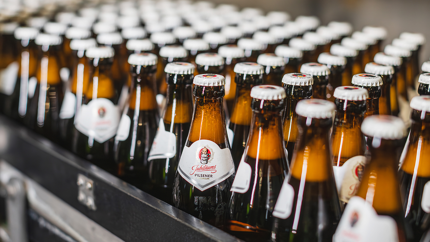 Viele braune Bierflaschen sind in Reihen in einer Kiste angeordnet. Einzelne Flaschen haben deutlich sichtbare Etiketten.