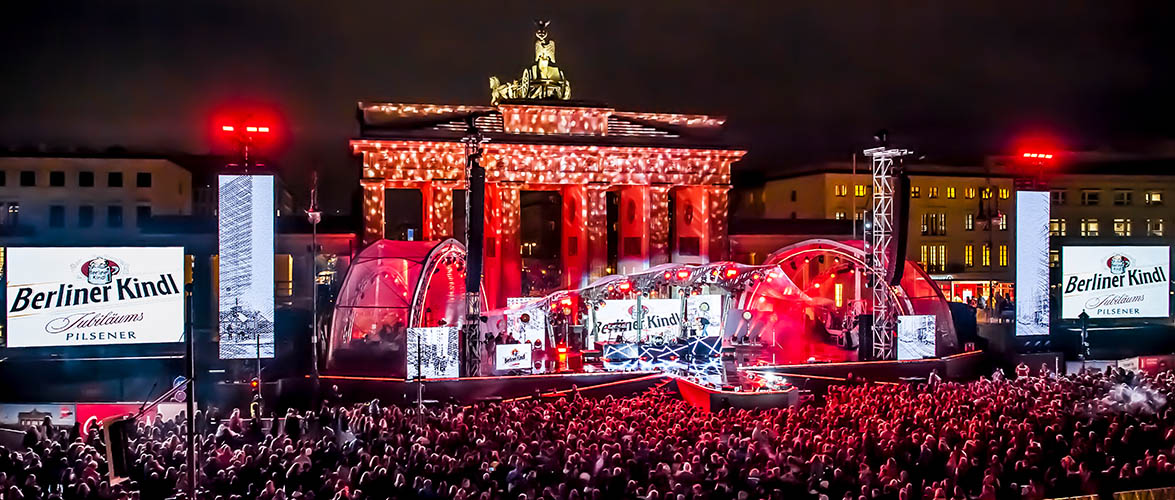 Menschen stehen vor dem Brandenburger Tor, wo eine Abendveranstaltung stattfindet.