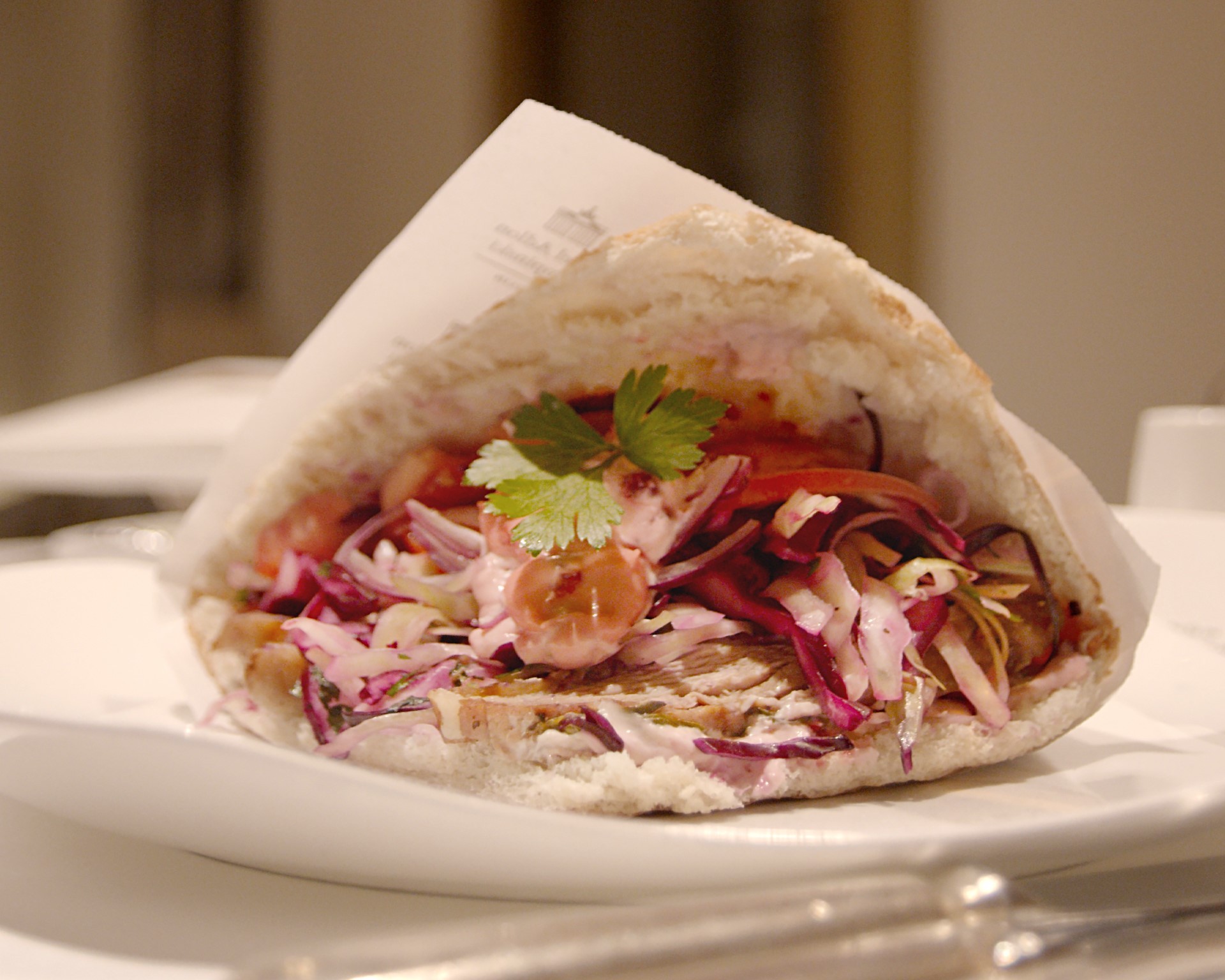 Ein gefülltes Fladenbrot liegt auf einem weißen Teller, garniert mit Rotkohl und Petersilie.