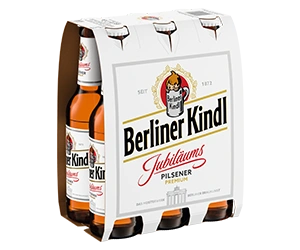 Sechs Bierflaschen der Sorte Jubiläums Pilsener in einem Papierträger der Marke Berliner Kindl.