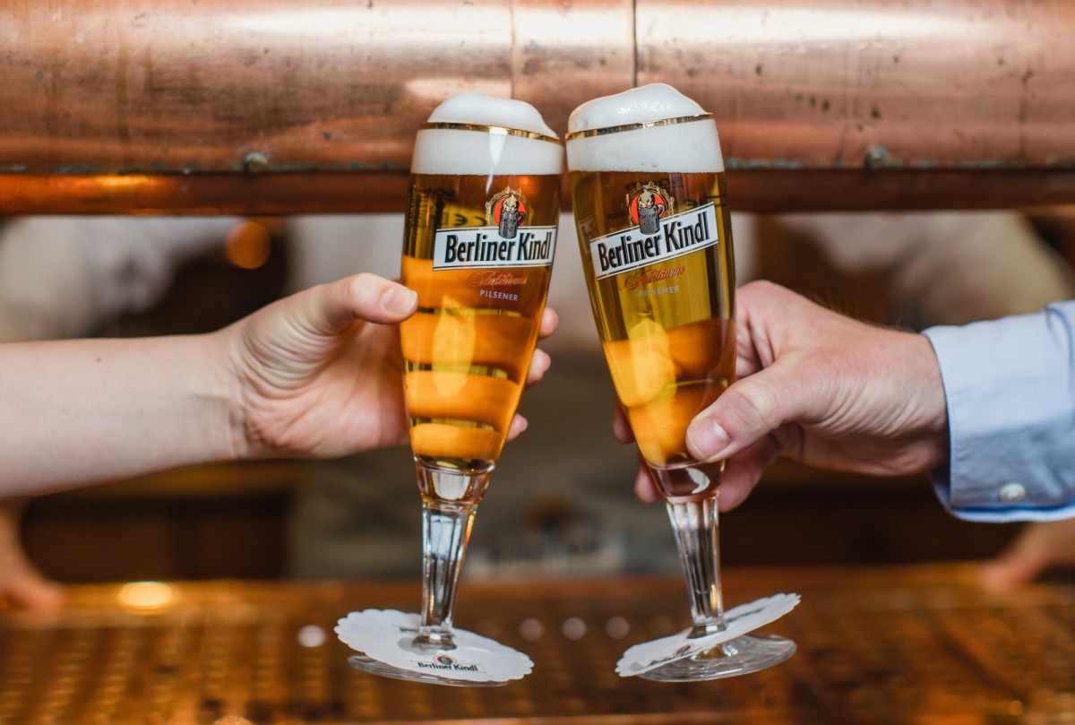 Eine betaute Flasche mit blauem Etikett mit der Aufschrift Berliner Kindl Jubiläums Pilsener Akloholfrei steht auf weißem Untergrund, die Ansicht ist von schräg oben.